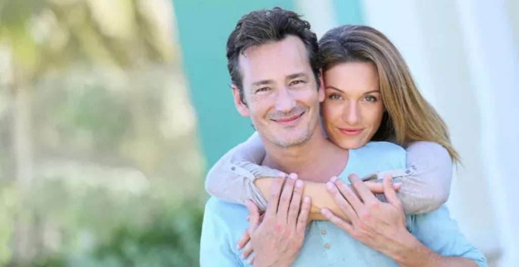 A man and woman hugging each other in front of a building.