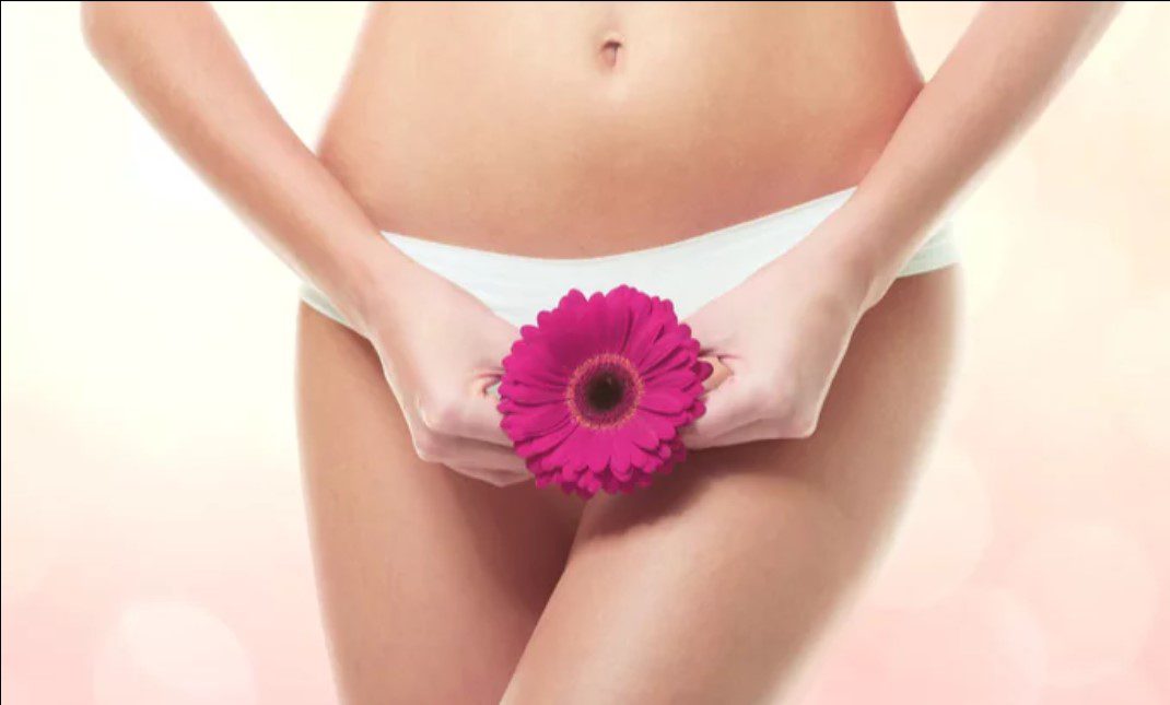 A woman holding a pink flower in her hands.