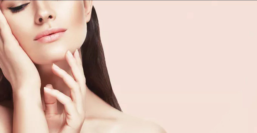 A woman with long hair is holding her face.