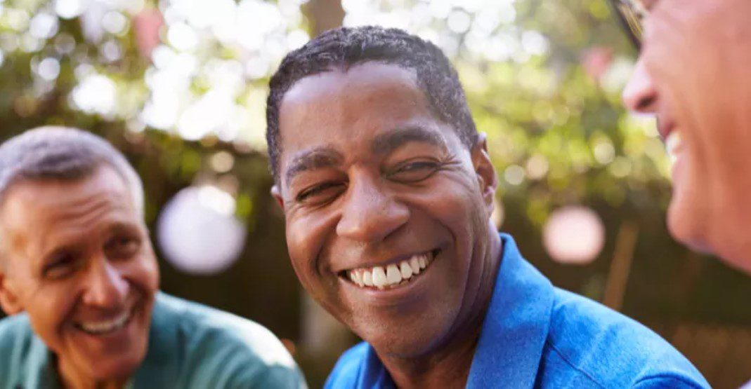 A man smiling for the camera with trees in the background.